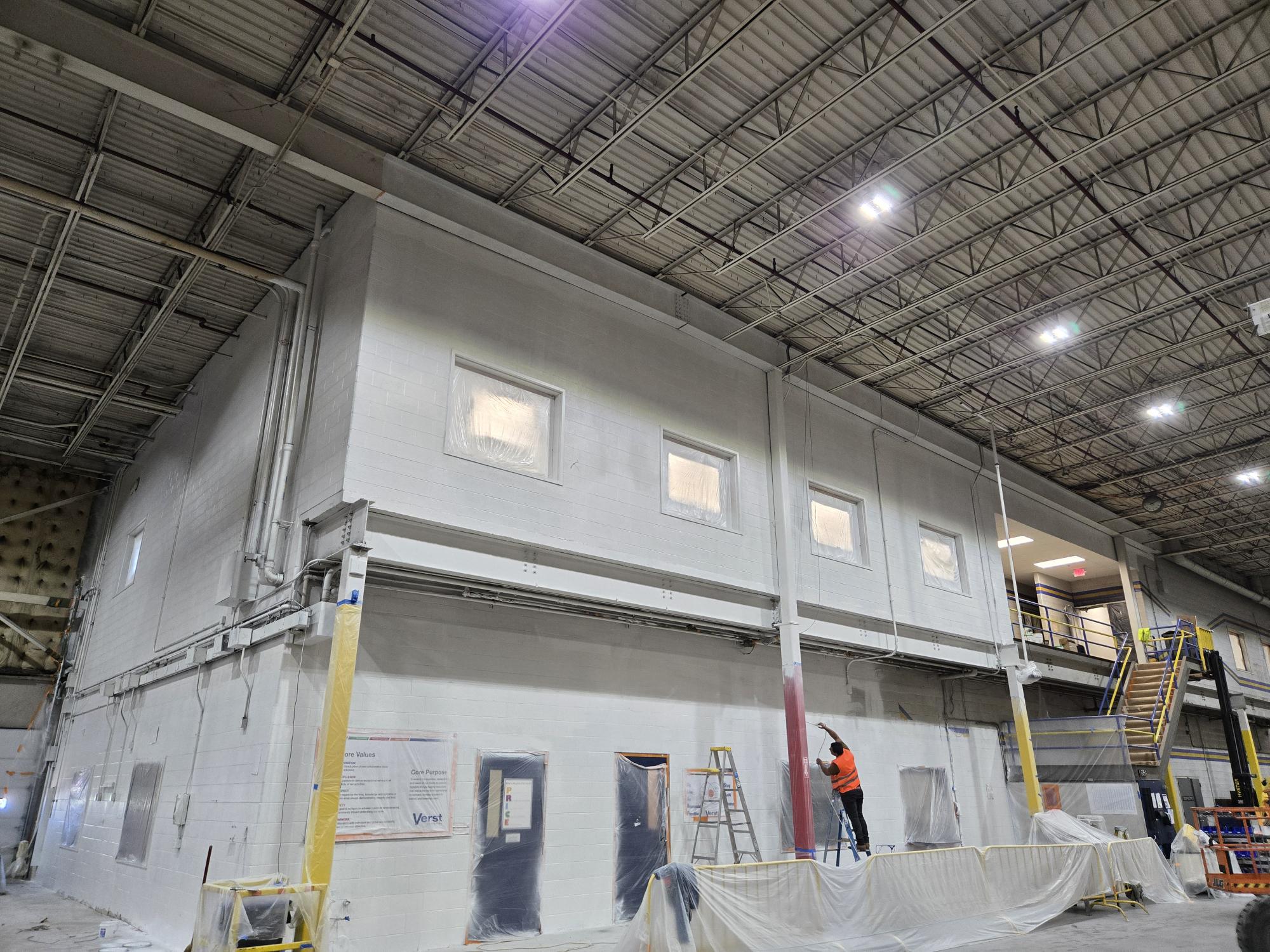Workers painting warehouse walls